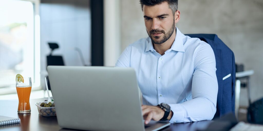 Joven hombre observa su notebook mientras escribe